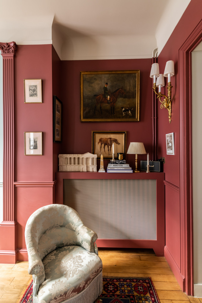 Modelo de salón cerrado tradicional de tamaño medio sin chimenea y televisor con paredes rojas, suelo de madera en tonos medios, suelo marrón y boiserie