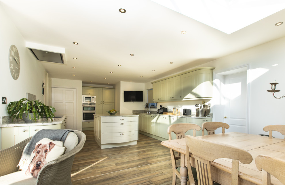 Inspiration for a large traditional galley eat-in kitchen in Hampshire with an undermount sink, shaker cabinets, green cabinets, granite benchtops, stainless steel appliances, porcelain floors, with island, beige floor and beige benchtop.
