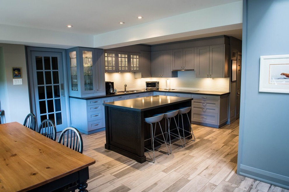 Photo of a mid-sized contemporary l-shaped open plan kitchen in Toronto with a double-bowl sink, shaker cabinets, blue cabinets, zinc benchtops, white splashback, stone slab splashback, stainless steel appliances, light hardwood floors and with island.