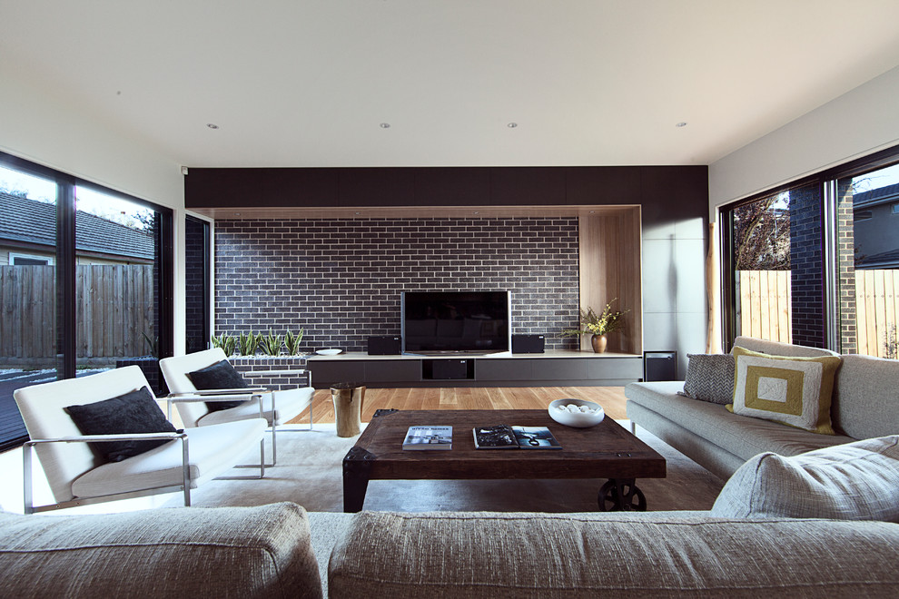 This is an example of a contemporary family room in Sydney with white walls, light hardwood floors and a freestanding tv.
