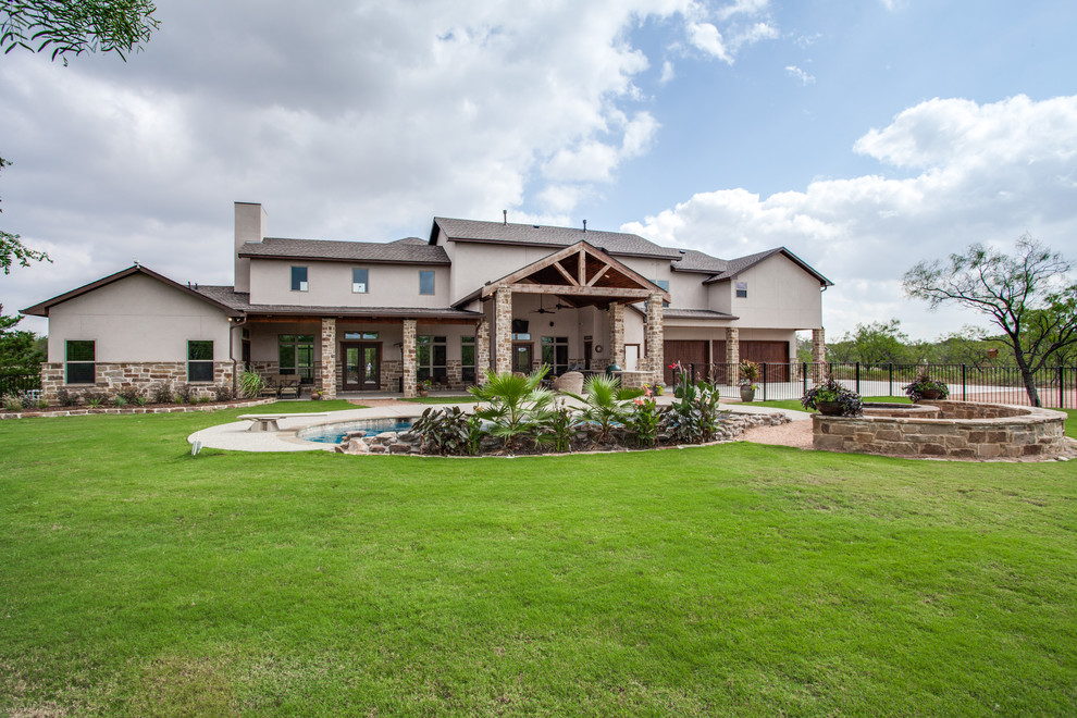This is an example of an expansive country two-storey beige exterior in Dallas with a gable roof and stone veneer.
