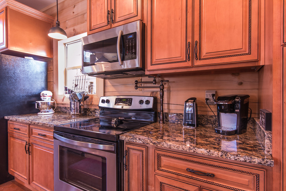 Mid-sized mountain style galley eat-in kitchen photo with an undermount sink, raised-panel cabinets, medium tone wood cabinets, granite countertops, wood backsplash, stainless steel appliances and an island