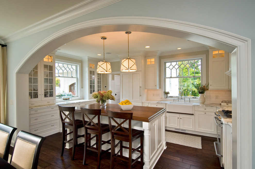 Traditional kitchen in New York with a farmhouse sink, wood benchtops and recessed-panel cabinets.