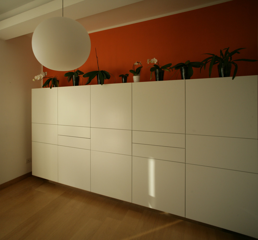 На фото: маленькая гостиная-столовая в современном стиле с оранжевыми стенами, деревянным полом, стандартным камином и фасадом камина из металла для на участке и в саду с