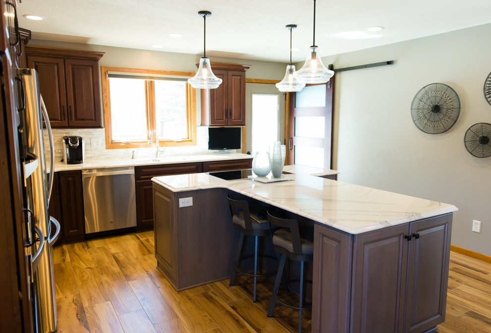 Mid-sized transitional ceramic tile and brown floor eat-in kitchen photo with brown cabinets, quartzite countertops, beige backsplash, ceramic backsplash, stainless steel appliances, an island and white countertops