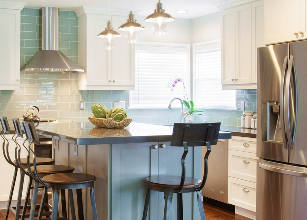 Inspiration for a mid-sized transitional l-shaped medium tone wood floor and brown floor open concept kitchen remodel in Orange County with an undermount sink, shaker cabinets, white cabinets, quartz countertops, green backsplash, glass tile backsplash, stainless steel appliances and an island