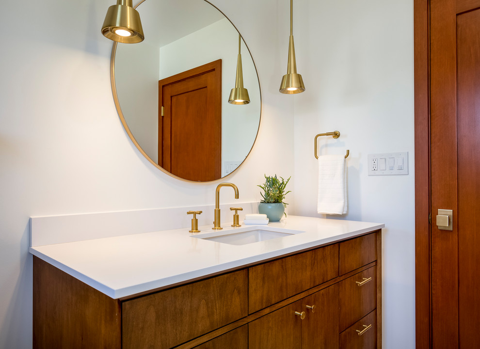 This is an example of a mid-sized midcentury bathroom in Los Angeles with medium wood cabinets, a shower/bathtub combo, white tile, ceramic tile, white walls, engineered quartz benchtops, furniture-like cabinets, a drop-in tub, a two-piece toilet, porcelain floors, an undermount sink, white floor and a hinged shower door.