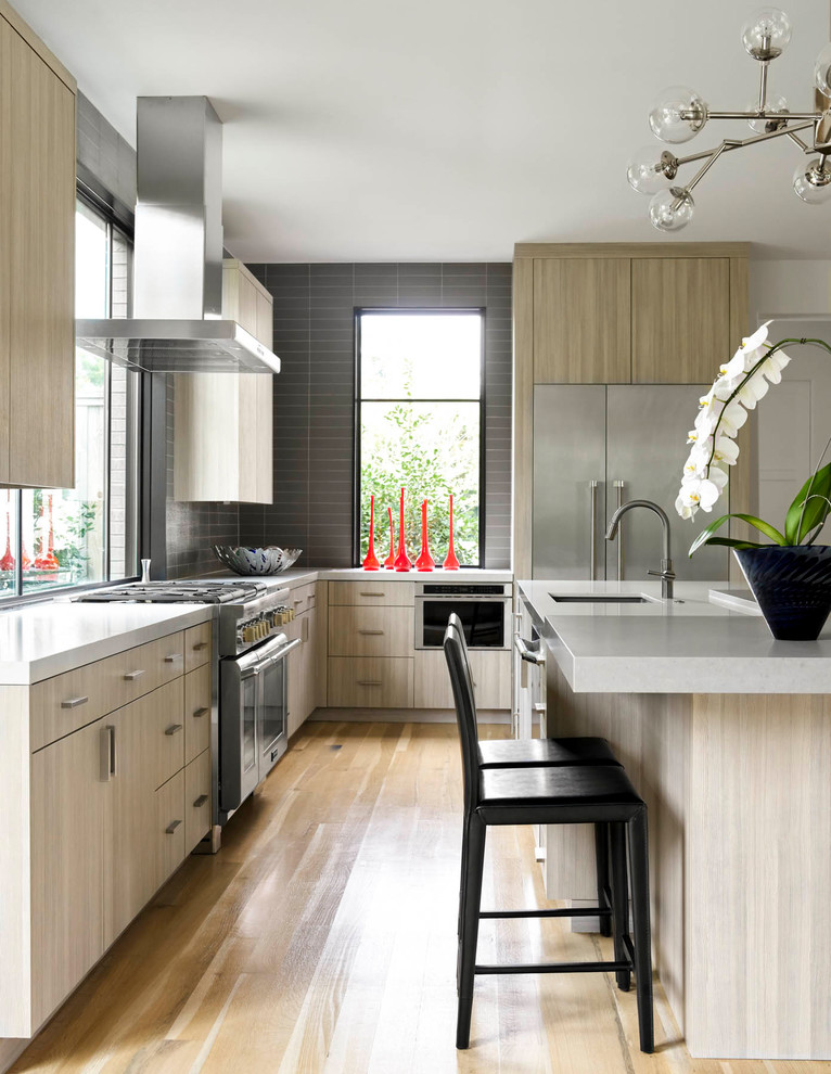 Design ideas for a contemporary l-shaped kitchen in Dallas with an undermount sink, flat-panel cabinets, light wood cabinets, grey splashback, stainless steel appliances, light hardwood floors and with island.