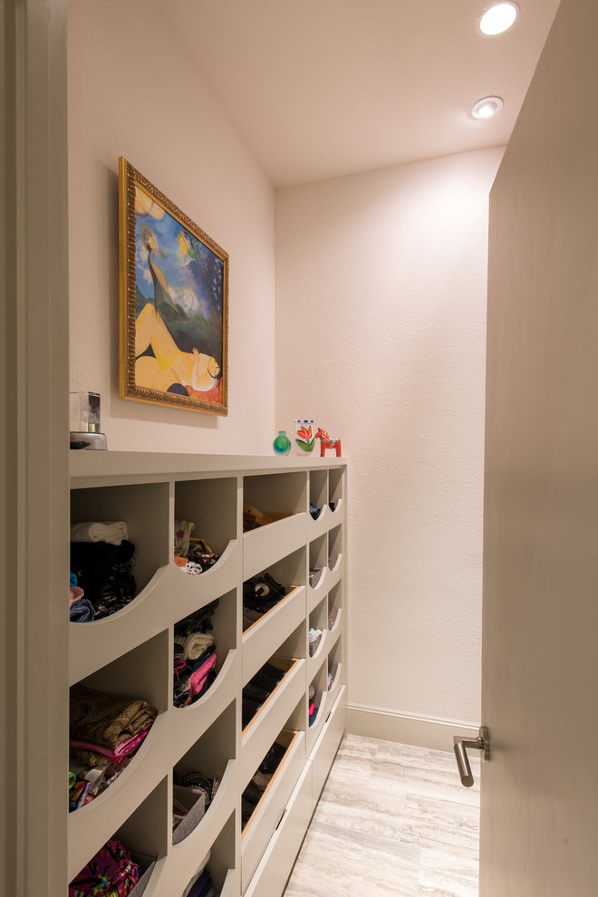 This is an example of a mid-sized contemporary women's walk-in wardrobe in Dallas with flat-panel cabinets, beige cabinets and marble floors.