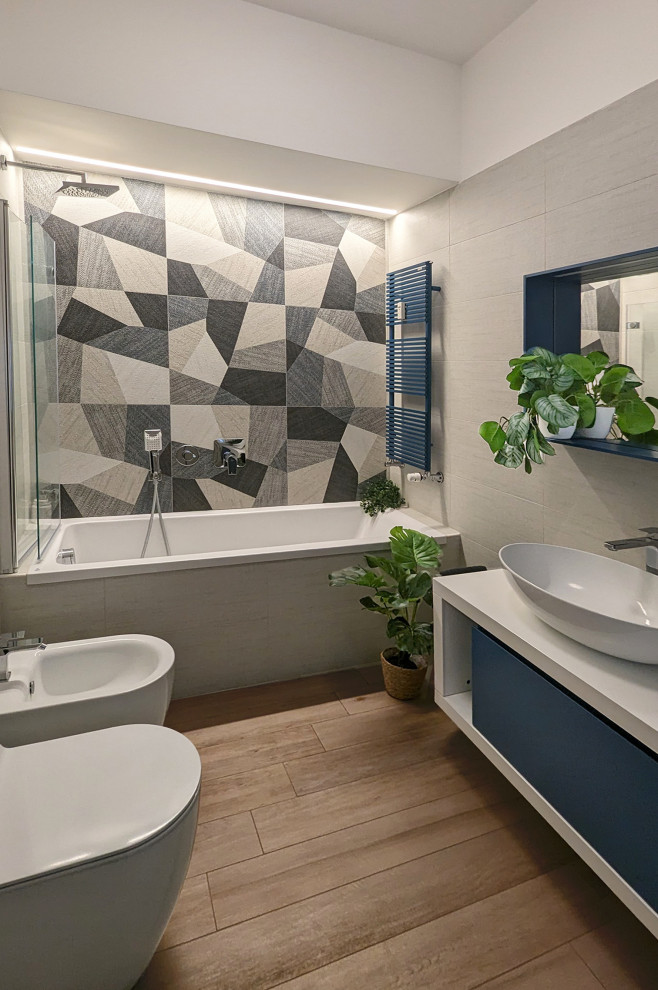 Exemple d'une salle de bain principale tendance de taille moyenne avec un placard à porte plane, des portes de placard bleues, une baignoire posée, un combiné douche/baignoire, un carrelage beige, des carreaux de porcelaine, un mur beige, parquet clair, meuble simple vasque, meuble-lavabo suspendu et un plafond décaissé.