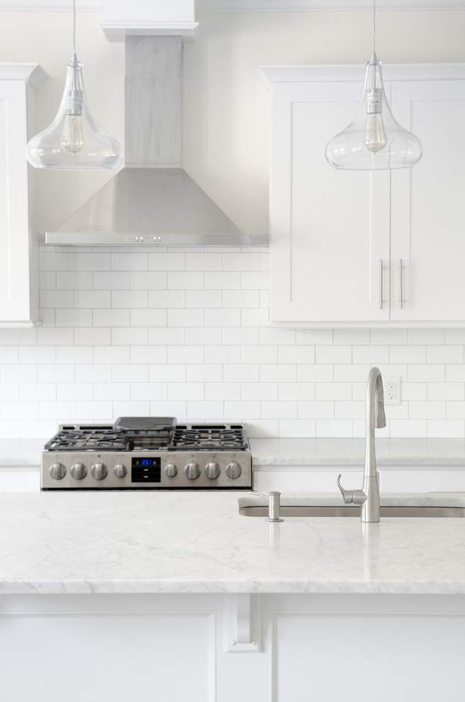 Inspiration for a large transitional single-wall dark wood floor and brown floor kitchen remodel in New York with an undermount sink, shaker cabinets, white cabinets, quartz countertops, white backsplash, subway tile backsplash, stainless steel appliances and an island