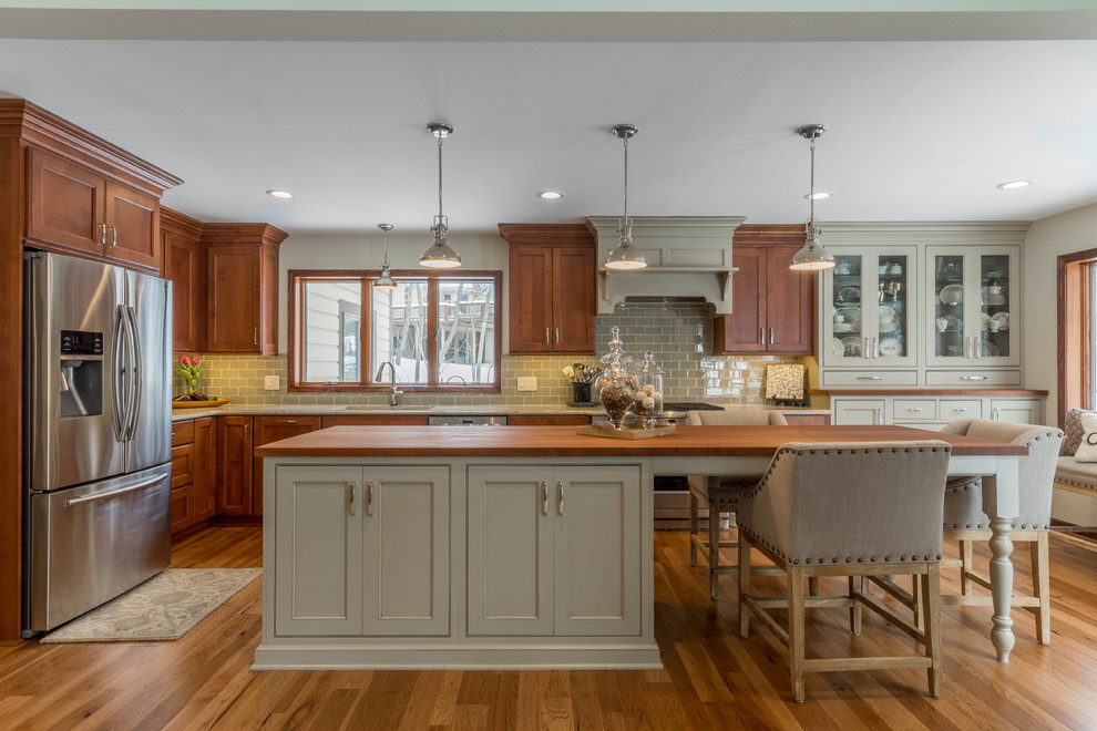Photo of a large traditional l-shaped kitchen in Detroit with an undermount sink, shaker cabinets, wood benchtops, green splashback, stainless steel appliances, medium hardwood floors, with island, medium wood cabinets and window splashback.