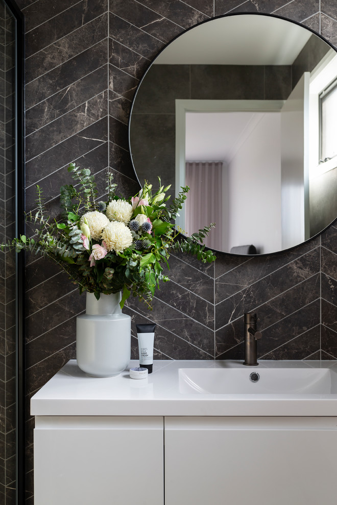 This is an example of a modern bathroom in Canberra - Queanbeyan with white cabinets, a wall-mount toilet, gray tile, porcelain tile, porcelain floors, an integrated sink and grey floor.