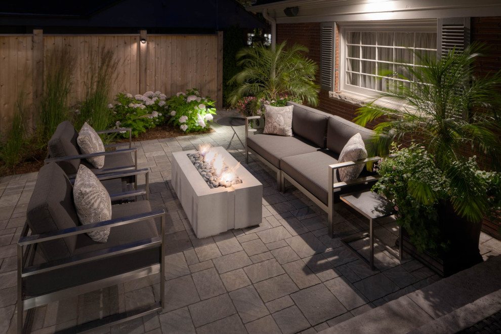 Large contemporary backyard patio in Toronto with natural stone pavers.