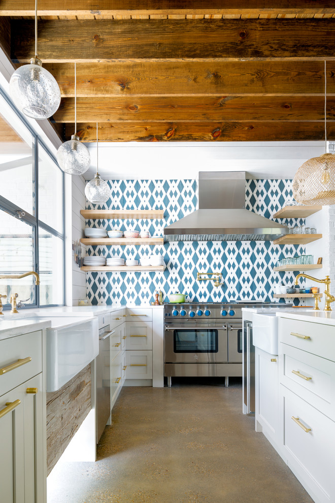 Inspiration for a country l-shaped kitchen in Austin with a farmhouse sink, shaker cabinets, white cabinets, multi-coloured splashback, cement tile splashback, stainless steel appliances, concrete floors, with island and grey floor.