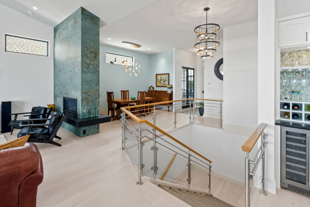 Exemple d'une salle à manger ouverte sur le salon tendance avec un mur bleu, parquet clair, une cheminée ribbon, un manteau de cheminée en carrelage, un sol beige et un plafond voûté.