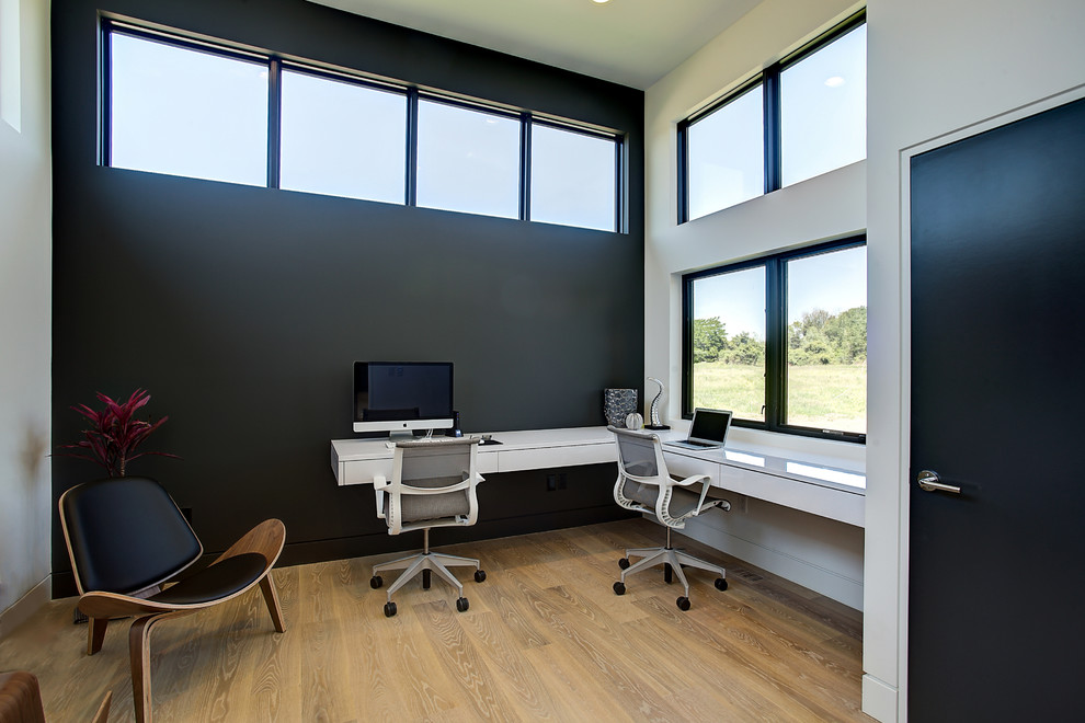 Mid-sized contemporary study room in Grand Rapids with black walls, light hardwood floors, a built-in desk, no fireplace and beige floor.