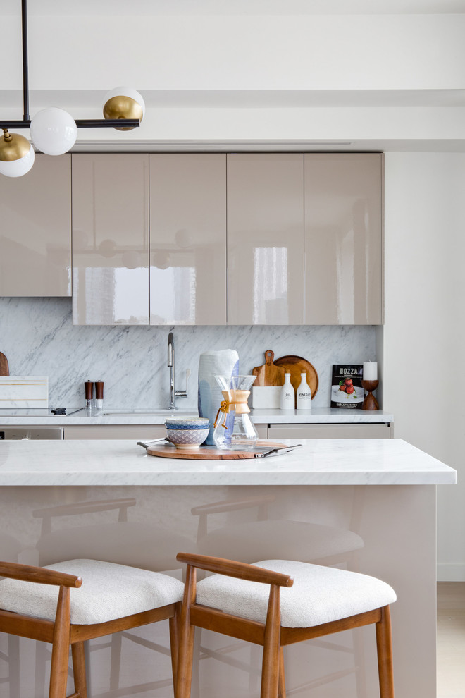 Inspiration for a large midcentury single-wall open plan kitchen in Los Angeles with flat-panel cabinets, beige cabinets, grey splashback, marble splashback, stainless steel appliances, light hardwood floors, with island, an undermount sink, marble benchtops and beige floor.