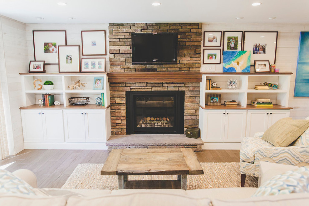 Inspiration for a mid-sized beach style open concept family room in Providence with a home bar, white walls, porcelain floors, a standard fireplace, a stone fireplace surround, a wall-mounted tv and brown floor.