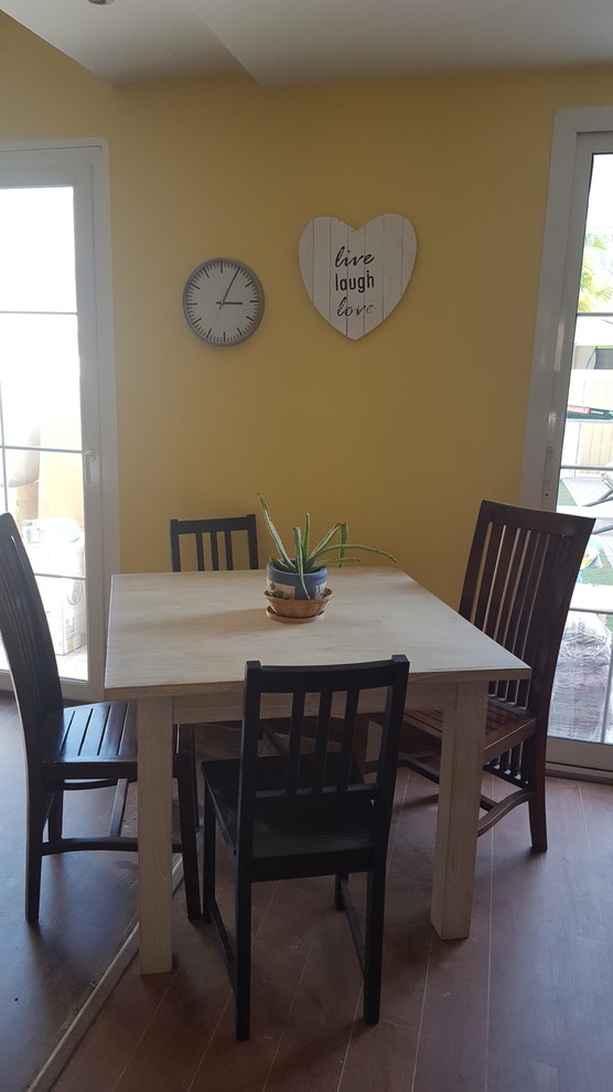 Foto di una piccola sala da pranzo contemporanea con pareti gialle e pavimento in laminato