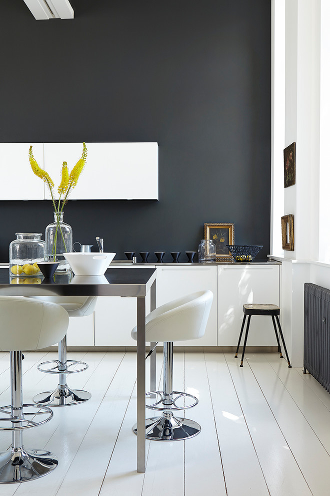 Example of a trendy white floor kitchen design in Belfast with flat-panel cabinets, black backsplash and an island