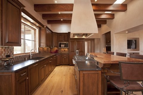 This is an example of a large traditional l-shaped eat-in kitchen in Albuquerque with an undermount sink, raised-panel cabinets, dark wood cabinets, quartz benchtops, multi-coloured splashback, glass tile splashback, stainless steel appliances, light hardwood floors and with island.