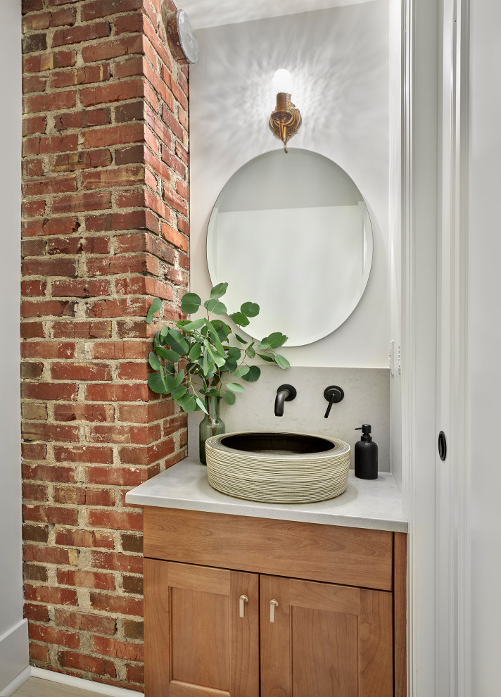 Small traditional powder room in Edmonton with shaker cabinets, medium wood cabinets, a one-piece toilet, white tile, ceramic tile, white walls, ceramic floors, a vessel sink, engineered quartz benchtops, beige floor, white benchtops, a built-in vanity and brick walls.