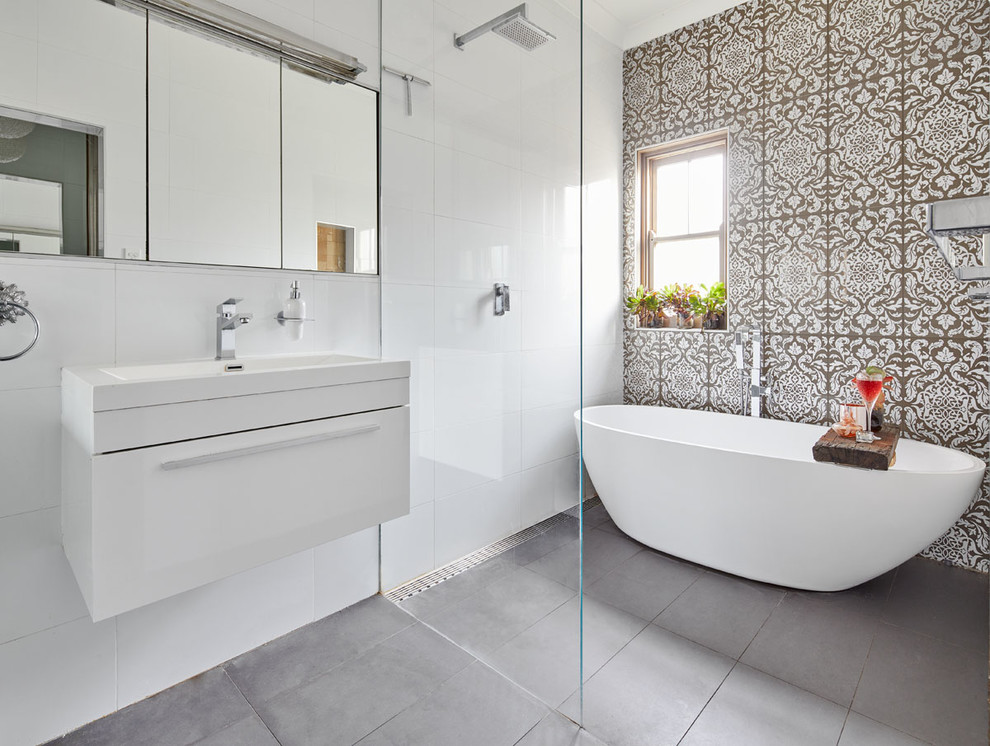 Mid-sized contemporary master wet room bathroom in Sydney with white cabinets, a freestanding tub, a wall-mount toilet, ceramic tile, white walls, ceramic floors, grey floor, an open shower, flat-panel cabinets, brown tile and a console sink.