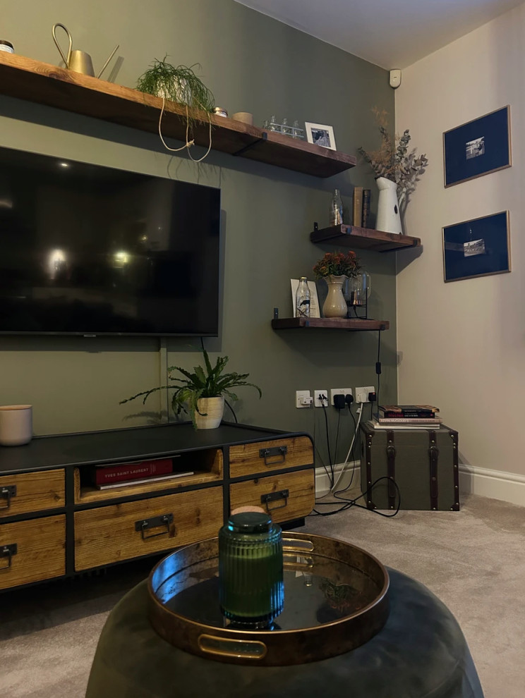 Стильный дизайн: изолированная гостиная комната среднего размера в стиле рустика с зелеными стенами, ковровым покрытием, телевизором на стене, бежевым полом и акцентной стеной - последний тренд