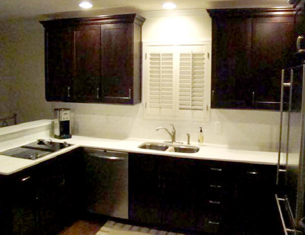 Large transitional u-shaped medium tone wood floor and brown floor eat-in kitchen photo in Houston with a double-bowl sink, raised-panel cabinets, dark wood cabinets, quartz countertops, white backsplash, ceramic backsplash, stainless steel appliances and no island