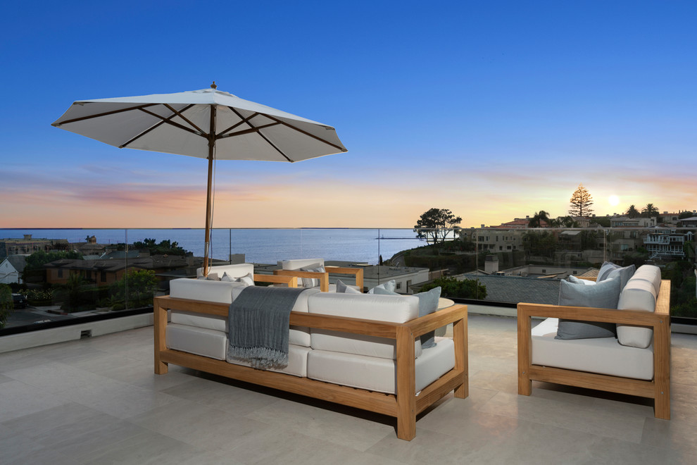 Inspiration for a large beach style balcony in Orange County with glass railing, no cover and a fire feature.