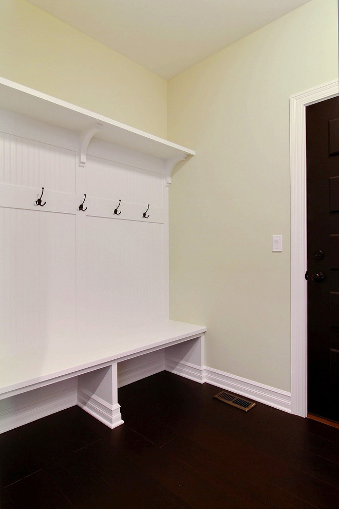 This is an example of a large traditional mudroom in Chicago with white walls, dark hardwood floors, a single front door and a black front door.