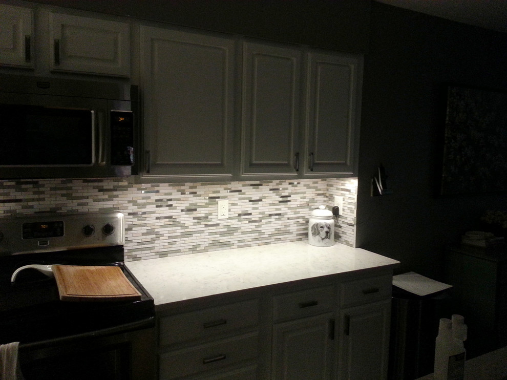 Inspiration for a mid-sized transitional u-shaped eat-in kitchen remodel with raised-panel cabinets, white cabinets, gray backsplash, stone tile backsplash, black appliances and granite countertops