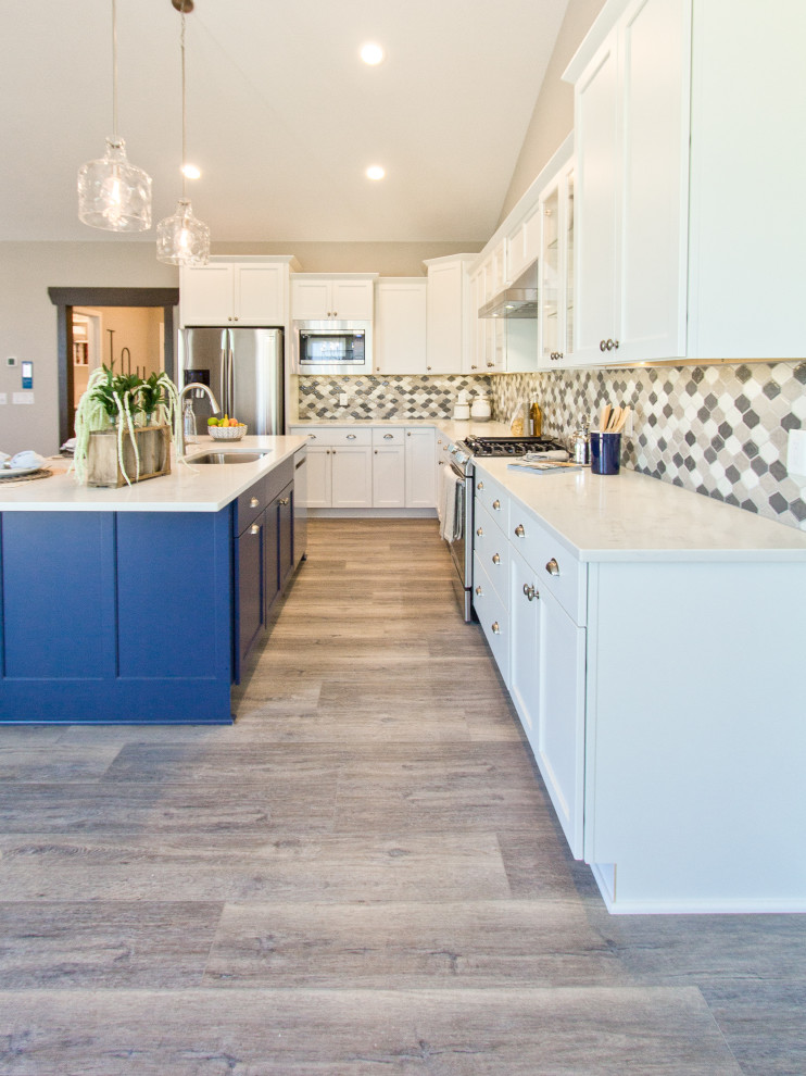 Transitional l-shaped brown floor and vinyl floor eat-in kitchen photo with an undermount sink, recessed-panel cabinets, white cabinets, quartz countertops, multicolored backsplash, mosaic tile backsplash, stainless steel appliances, an island and white countertops