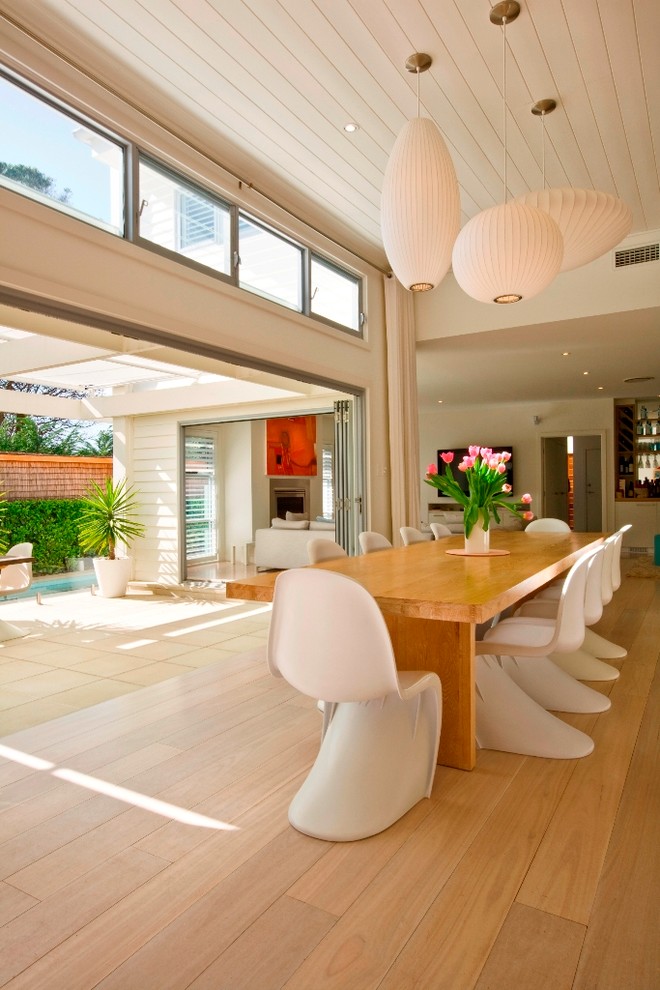 This is an example of a contemporary dining room in Sydney with beige walls and medium hardwood floors.