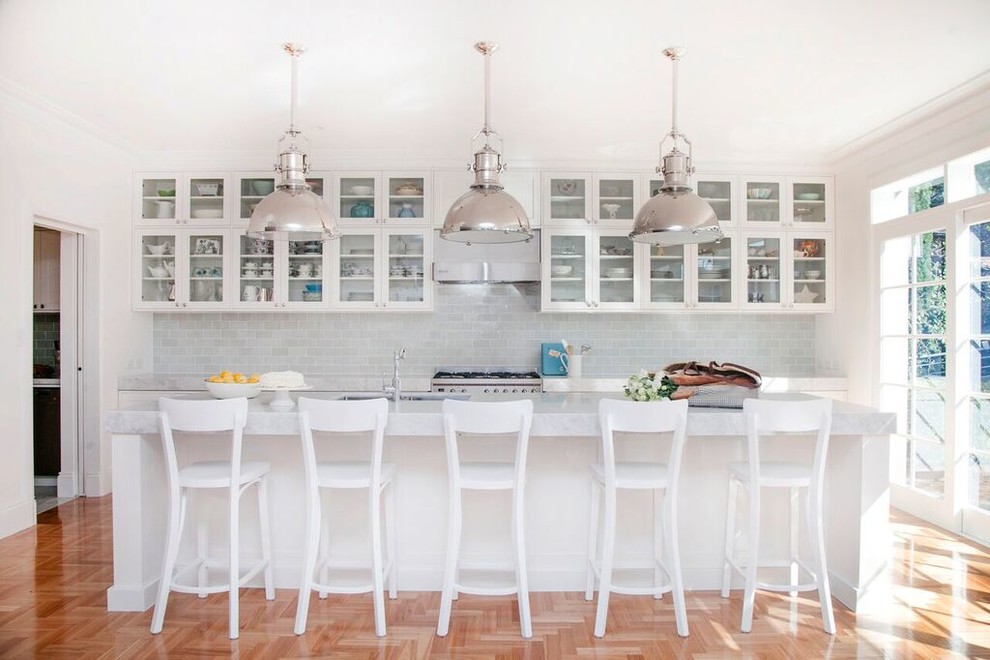 Photo of a mid-sized transitional galley eat-in kitchen in Sydney with an undermount sink, glass-front cabinets, white cabinets, marble benchtops, grey splashback, glass tile splashback, stainless steel appliances, medium hardwood floors and with island.