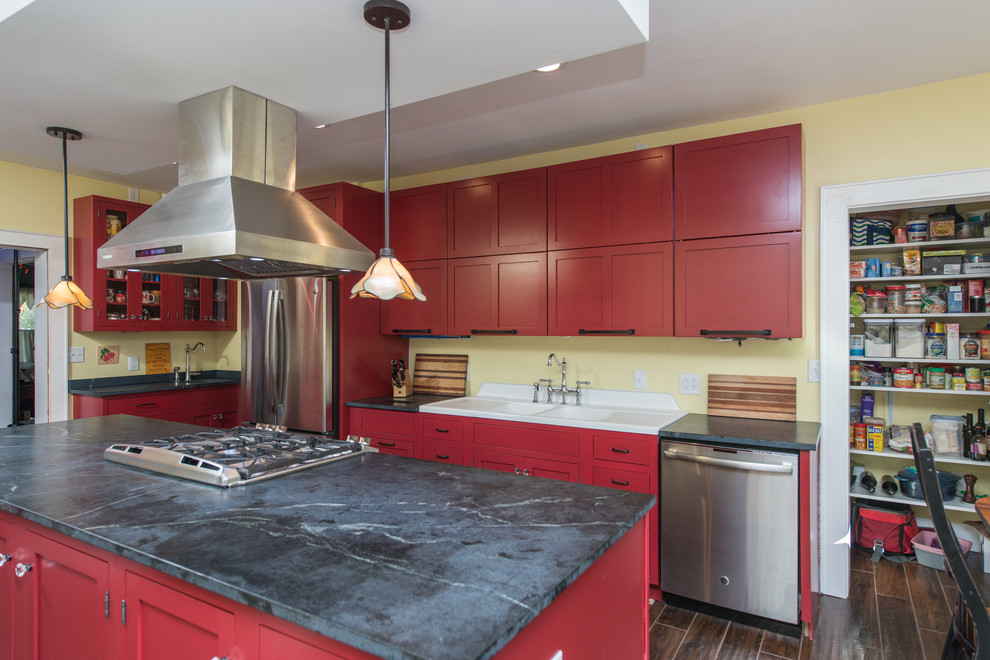 Inspiration for a mid-sized contemporary galley dark wood floor and brown floor eat-in kitchen remodel with a double-bowl sink, raised-panel cabinets, red cabinets, soapstone countertops, stainless steel appliances and an island