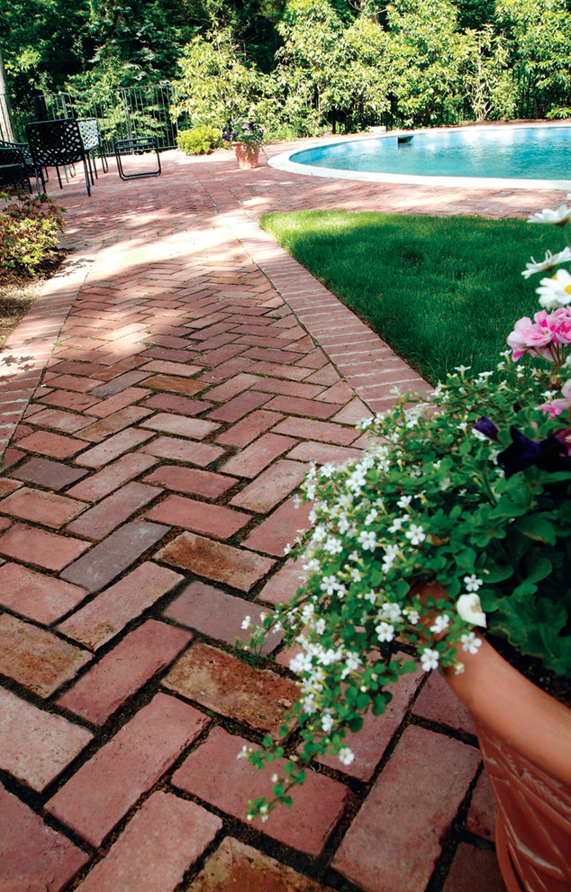 Large traditional backyard garden in New York with brick pavers and with path.