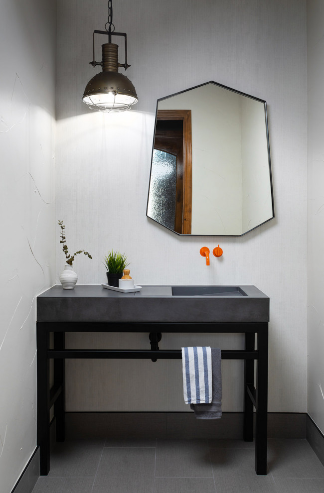 Mid-sized industrial bathroom in Denver with black cabinets, a one-piece toilet, white walls, ceramic floors, a console sink, concrete benchtops, grey floor, grey benchtops, a single vanity, a freestanding vanity and wallpaper.