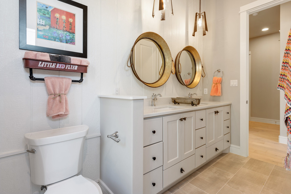 Photo of a country bathroom in Austin with flat-panel cabinets, white cabinets, a two-piece toilet, white walls, an undermount sink, beige floor and white benchtops.