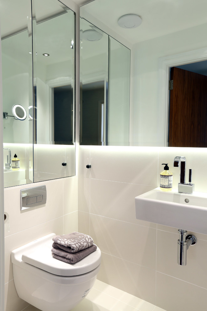 Photo of a contemporary powder room in London with a wall-mount sink, a wall-mount toilet and beige tile.