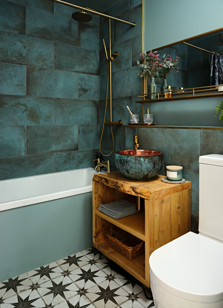 This is an example of a small eclectic kids bathroom in London with open cabinets, distressed cabinets, a drop-in tub, a shower/bathtub combo, green tile, porcelain tile, porcelain floors, a console sink, wood benchtops, black floor, a shower curtain, a single vanity and a freestanding vanity.