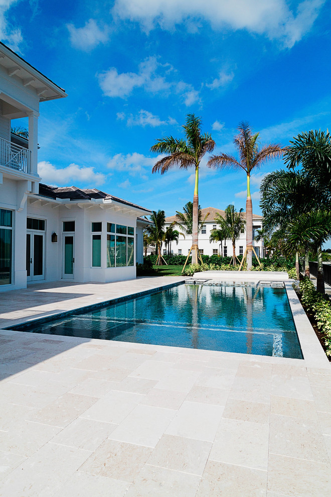Mid-sized tropical backyard pool in Miami with natural stone pavers.