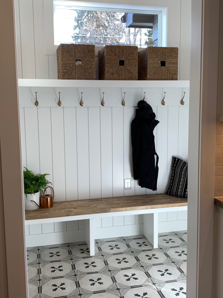 Example of a transitional porcelain tile, multicolored floor and shiplap wall entryway design with white walls