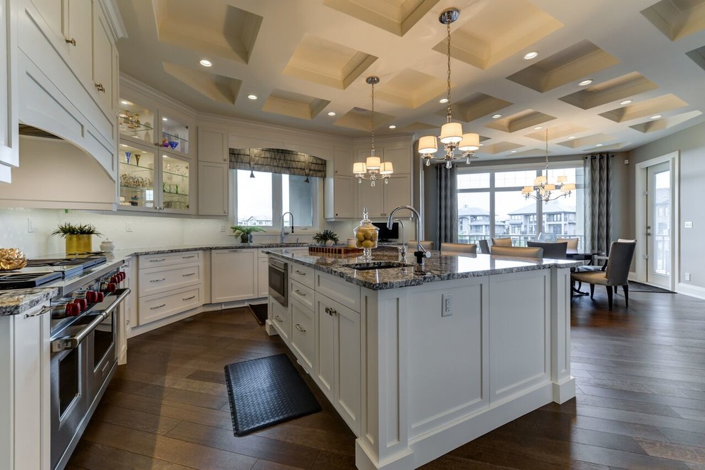 Kitchen - large transitional u-shaped medium tone wood floor and brown floor kitchen idea in Edmonton with shaker cabinets, white cabinets, granite countertops, white backsplash, an island, an undermount sink, glass tile backsplash and paneled appliances
