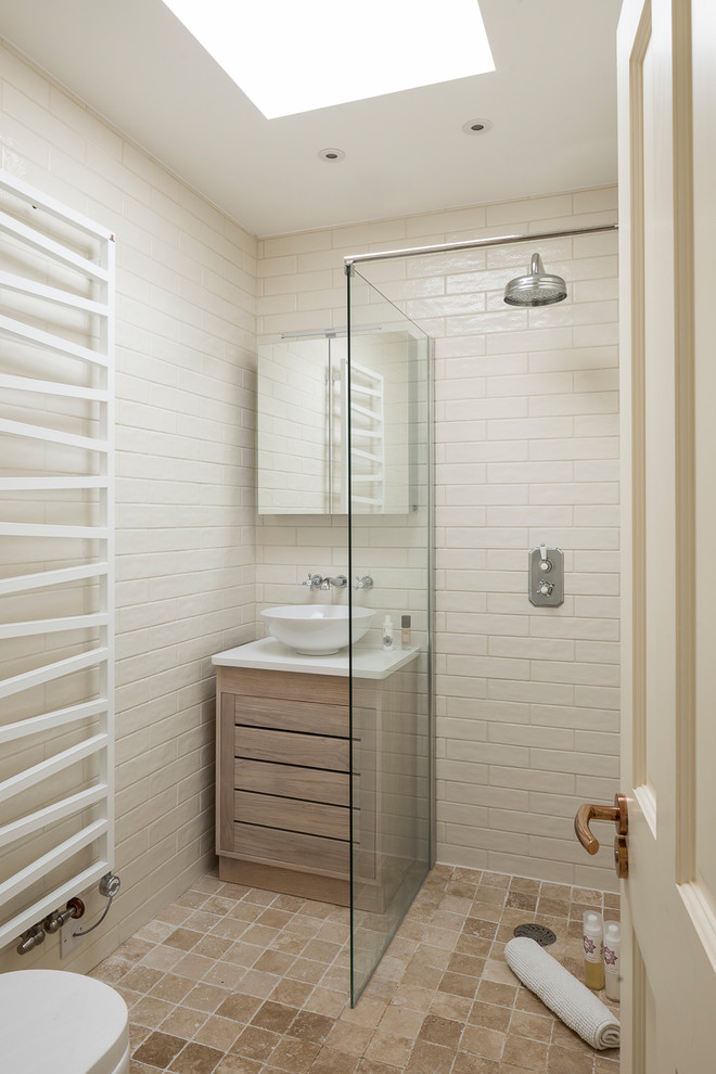 Inspiration for a small transitional 3/4 bathroom in London with flat-panel cabinets, light wood cabinets, an open shower, a wall-mount toilet, beige tile, porcelain tile, beige walls, terra-cotta floors, a vessel sink, solid surface benchtops, beige floor and an open shower.