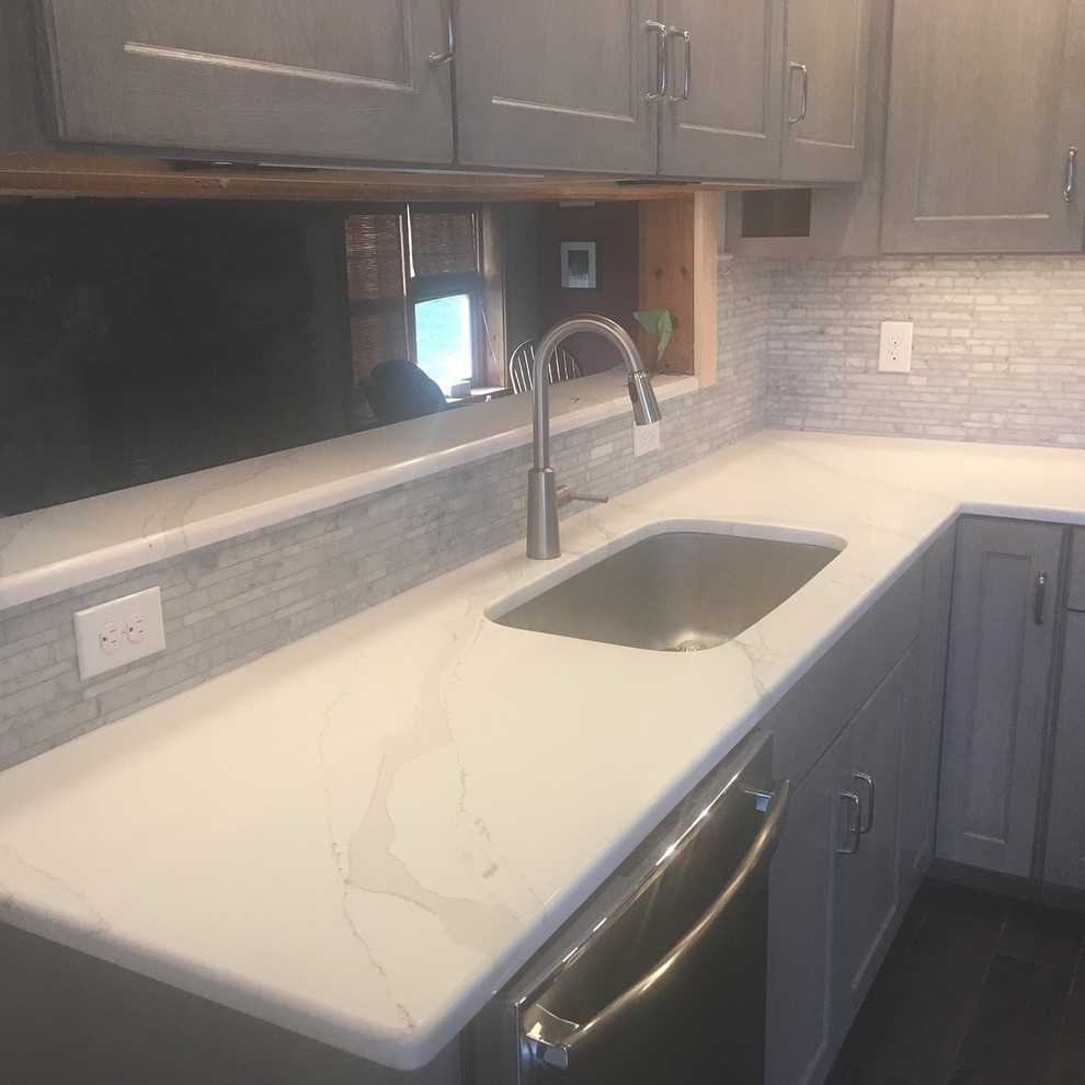 Inspiration for a mid-sized transitional u-shaped kitchen remodel in Boston with an undermount sink, recessed-panel cabinets, gray cabinets, quartzite countertops, gray backsplash, stone tile backsplash, stainless steel appliances, no island and white countertops