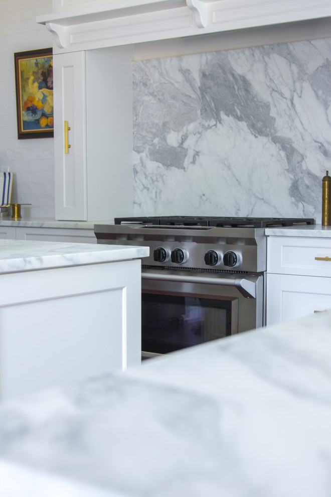 Inspiration for a transitional u-shaped dark wood floor and brown floor kitchen remodel with a farmhouse sink, shaker cabinets, white cabinets, marble countertops, marble backsplash, stainless steel appliances and an island