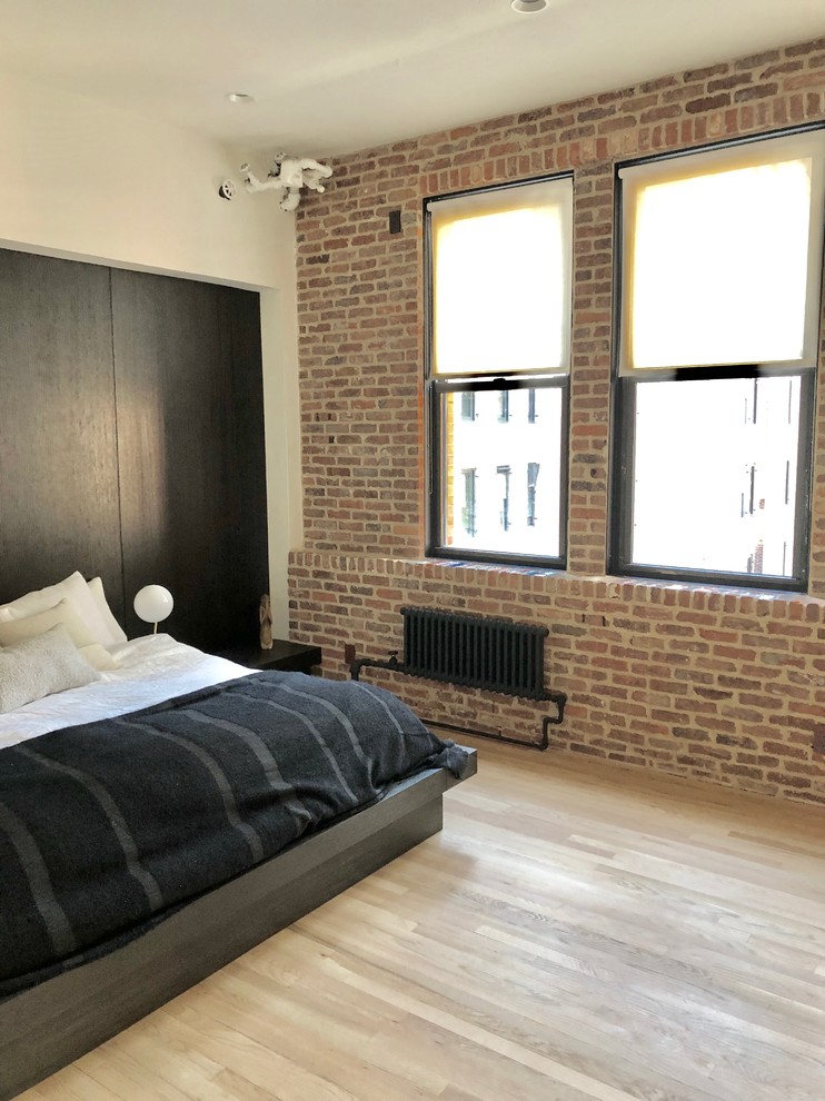 Design ideas for a mid-sized industrial loft-style bedroom in New York with multi-coloured walls, light hardwood floors and beige floor.