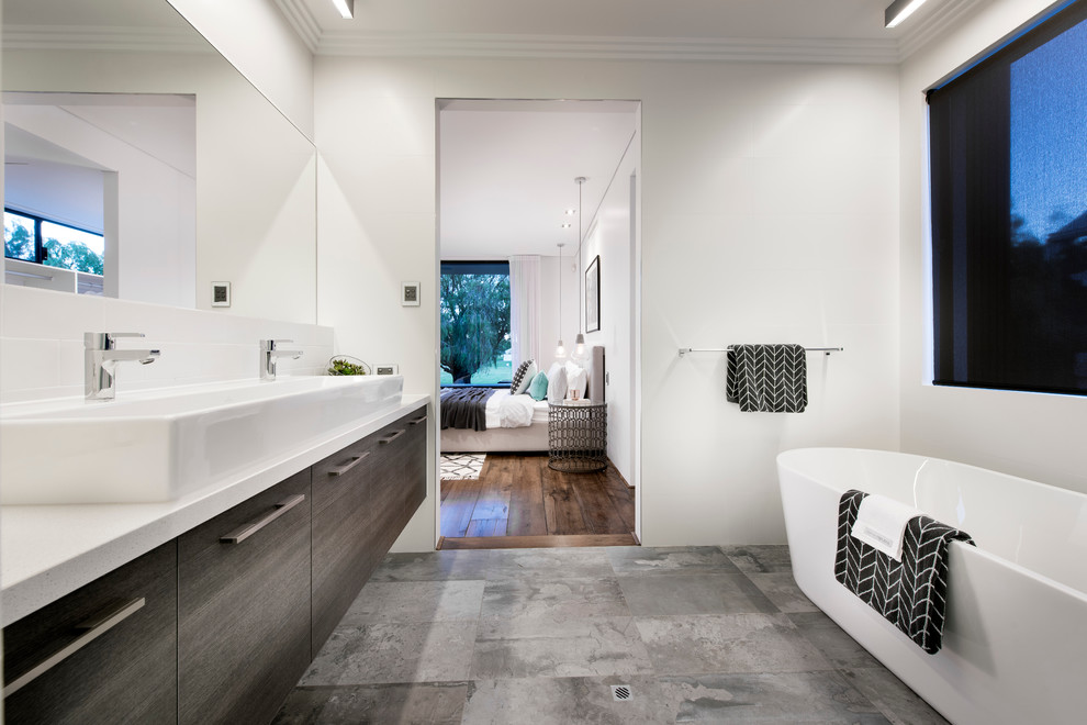 Inspiration for a mid-sized industrial master bathroom in Perth with a trough sink, beaded inset cabinets, a freestanding tub, an alcove shower, a one-piece toilet, gray tile, porcelain tile, white walls, porcelain floors and dark wood cabinets.